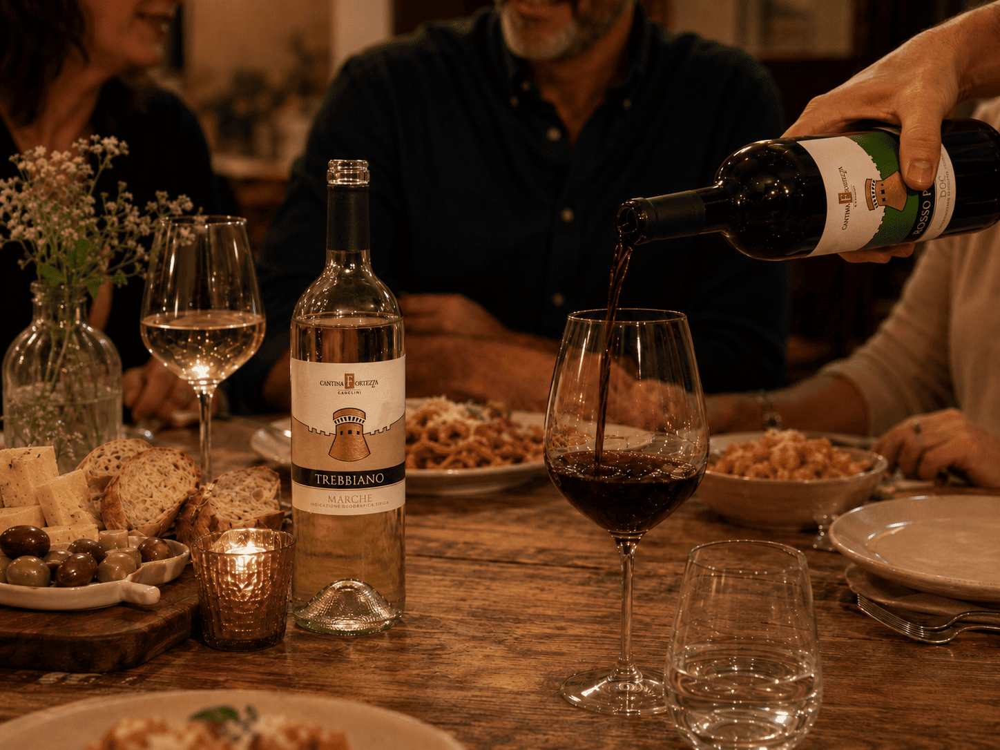 Persona che versa vino rosso a tavola accanto a una bottiglia Cantina Fortezza Marche